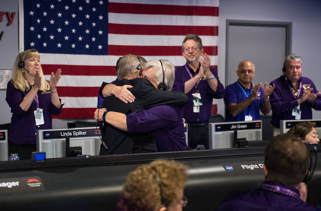Менеджер программы Cassini, менеджер по работе с командами, Эрл Мэйз, слева, и менеджер миссии корабля Кассини на Сатурне, Джули Уэбстер обнимаются после того, как космический корабль Кассини погрузился в Сатурн, в пятницу, 15 сентября 2017 года. Лабораторию реактивного движения НАСА в Пасадене, США. Фото: NASA (СС0).